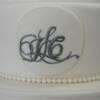 Close-up of the hand piped monogram and and edible sugar pearls on the middle tier of the Ivory Banded wedding cake.
