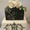 Two tiered black and white cake. Edible sugar roses and leaves sit on top of this hand piped cake.