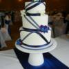 3 tier round wedding cake with Nay Blue Ribbon criss-crossed over the cake. Fresh orchids decorate this cake that was placed on our White, Round, English cake stand.