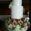 4 tier round wedding cake with a second, double high tier that had a lace design added to it. The third, half height tier was hand painted with a red tartan design replicating the kilt worn by the groom. Fresh flowers cover the bottom tier of this 18" high wedding cake!