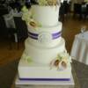 4 tier round and square wedding cake with lace designs, a hand drawn "&" with royal purple and silver accents. Sugar Cala Lillies and orchids were added on delivery to Hotel Eldorado. 