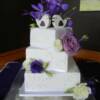 3 tier Square Wedding Cake with Pearl Piping and assorted fresh flowers sitting on our clear acrylic sqaure cake stand filled with rose petals. 