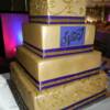 4 tier square Gold and Purple wedding cake with hand-piped scroll work. 