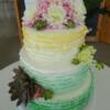 3 tier round fondant ruffle cake with spearmint green to pale coral ombre design and fresh flowers.