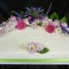 12X18 Birthday Cake with fresh flowers and the birthday names of this family piped onto the side of the cake. 