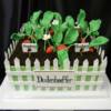Strawberry Patch Celebration Cake made for a family reunion. A white "picket fence" was added around the outside of this cake, and then we added oreo crumbs for dirt, and fondant sculpted strawberries, blossoms and leaves for the strawberry plants. 